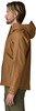 Ein Mann in einer braunen Jacke und grüner Hose steht seitlich zur Kamera.