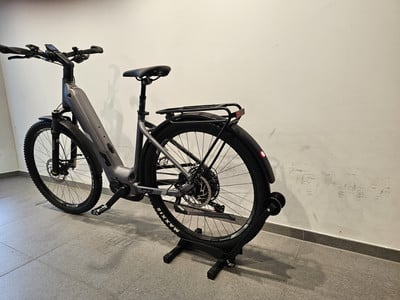 Ein graues E-Bike mit Schutzblechen und Gepäckträger steht auf dem Boden. Ein graues E-Bike mit Schutzblechen und Gepäckträger steht auf dem Boden.