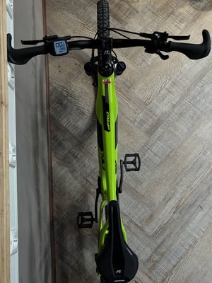 Ein grünes E-Bike mit Display am Lenker hängt an der Wand. Ein grünes E-Bike mit Display am Lenker hängt an der Wand.