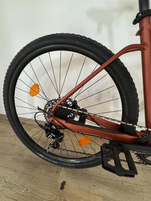 Das Hinterrad eines Fahrrads mit orangefarbenem Reflektor und Schaltwerk.
