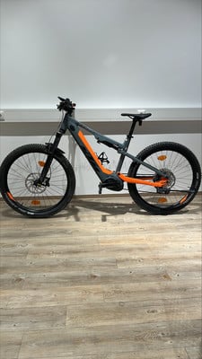 Graues E-Bike mit orangefarbenen Akzenten auf Holzboden. Graues E-Bike mit orangefarbenen Akzenten auf Holzboden.