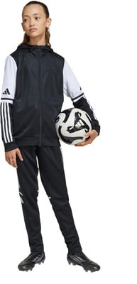 Mädchen im schwarz-weißen Adidas-Anzug hält einen Fußball.