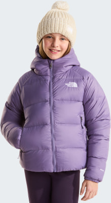 Mädchen in Daunenjacke und Strickmütze lächelt in die Kamera.