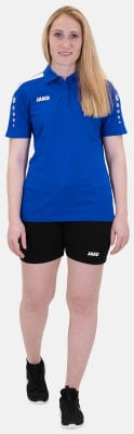 Eine Frau in einem blauen Hemd und schwarzen Shorts posiert vor weißem Hintergrund.