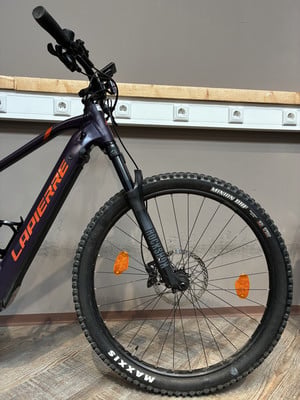 Lila Mountainbike mit orangefarbenem LAPIERRE-Logo und RockShox-Federung. Lila Mountainbike mit orangefarbenem LAPIERRE-Logo und RockShox-Federung.
