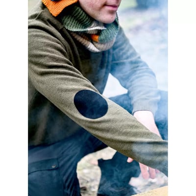 Mann im grünen Pullover mit Lederflicken an den Ellbogen und buntem Schal. Mann im grünen Pullover mit Lederflicken an den Ellbogen und buntem Schal.