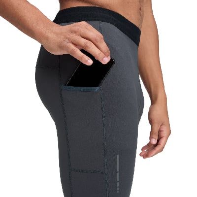 Egy férfi telefont tesz a sötétszürke leggins zsebébe.