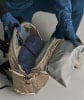 Eine Person packt eine blaue Jacke in einen beigen Rucksack.