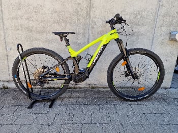 Ein gelbes Mountainbike mit schwarzen Akzenten steht vor einer Wand.