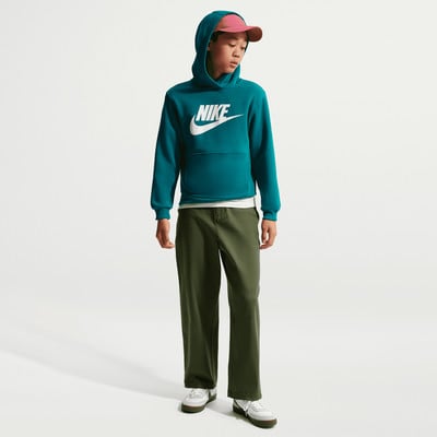 Ein Junge in einem teal farbenen Nike Hoodie und dunkelgrüner Hose.