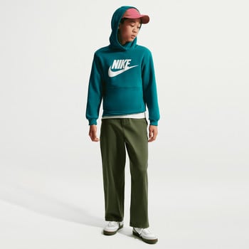 Ein Junge in einem teal farbenen Nike Hoodie und dunkelgrüner Hose.