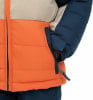 Detail einer Jacke mit orangefarbenem und beigem Oberteil und dunkelblauem Ärmelteil.