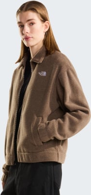 Eine Frau in einer braunen Fleecejacke mit The North Face Logo und schwarzer Hose. Eine Frau in einer braunen Fleecejacke mit The North Face Logo und schwarzer Hose.
