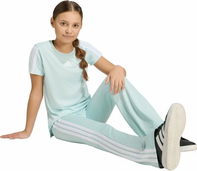 Ein Mädchen in mintgrüner Adidas-Kleidung sitzt auf dem Boden. Ein Mädchen in mintgrüner Adidas-Kleidung sitzt auf dem Boden.