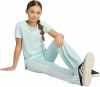 Ein Mädchen in mintgrüner Adidas-Kleidung sitzt auf dem Boden.