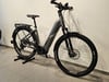 Graues E-Bike mit Gepäckträger und Federung auf einem Ständer.