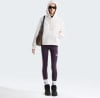 Eine Frau in einem cremefarbenen Hoodie, lila Leggings und Sonnenbrille.