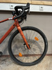 Orange Gravelbike mit schwarzem Lenker und vorderer Scheibenbremse.