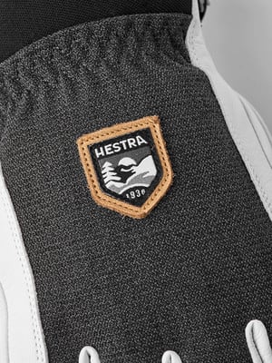 Detail des HESTRA-Logos mit Bergen und dem Jahr 1936 auf einem Handschuh.