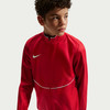 Junge in roter Jacke mit weißem Nike-Logo und weißem Streifen.