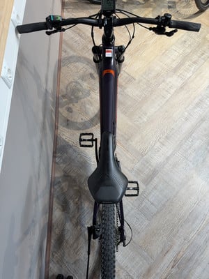 Oberansicht eines dunkelvioletten E-Bikes mit schwarzem Sattel und Lenker. Oberansicht eines dunkelvioletten E-Bikes mit schwarzem Sattel und Lenker.