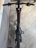 Oberansicht eines dunkelvioletten E-Bikes mit schwarzem Sattel und Lenker.