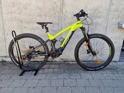Ein gelbes Mountain-E-Bike mit schwarzem Rahmen steht auf einem Ständer.