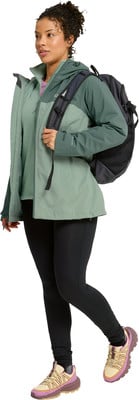 Eine Frau in einer grünen Jacke und schwarzen Leggings mit Rucksack. Eine Frau in einer grünen Jacke und schwarzen Leggings mit Rucksack.
