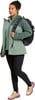 Eine Frau in einer grünen Jacke und schwarzen Leggings mit Rucksack.