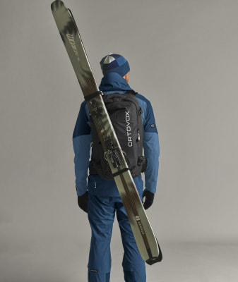 Ein Mann mit Skiern auf dem Rücken in blauer Kleidung und Rucksack. Ein Mann mit Skiern auf dem Rücken in blauer Kleidung und Rucksack.