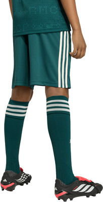 Kind in dunkelgrüner Sportkleidung mit weißen Streifen und Fußballschuhen. Kind in dunkelgrüner Sportkleidung mit weißen Streifen und Fußballschuhen.
