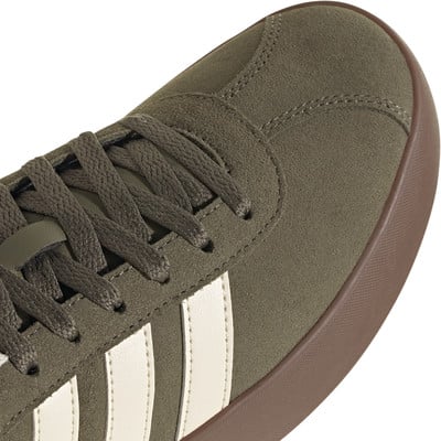 Grüner Adidas Wildleder-Sneaker mit weißen Streifen und brauner Sohle.