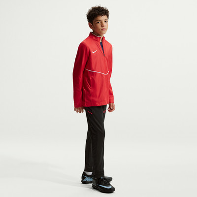 Ein Junge in einer roten Jacke und schwarzen Hosen steht seitlich vor einem weißen Hintergrund. Ein Junge in einer roten Jacke und schwarzen Hosen steht seitlich vor einem weißen Hintergrund.