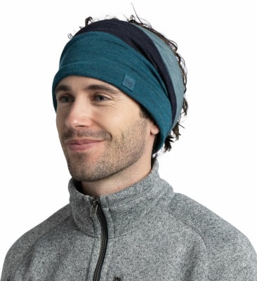 Ein Mann mit dunklen Haaren trägt ein gestreiftes Stirnband und einen grauen Pullover. Ein Mann mit dunklen Haaren trägt ein gestreiftes Stirnband und einen grauen Pullover.
