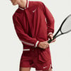Mann in roter Nike-Jacke und Shorts hält einen Tennisschläger.