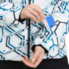 Eine Frau steckt eine Karte in die Tasche einer Jacke mit geometrischem Muster.