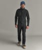 Ein Mann in dunkler Jacke, Hose und blauer Mütze mit Skischuhen.
