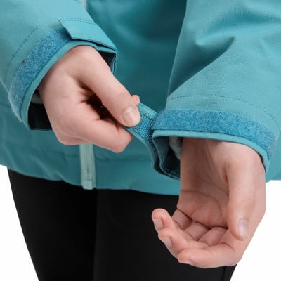 Eine Hand schließt den Klettverschluss am Ärmel der Jacke.