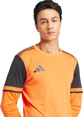 Ein Mann in einem orangefarbenen Hemd mit schwarzen Ärmeln und Adidas-Logo.