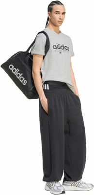 Férfi sporttáskával a vállán és fekete Adidas melegítőnadrágban. Férfi sporttáskával a vállán és fekete Adidas melegítőnadrágban.