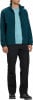 Ein Mann in einem dunkelblauen Fleece-Pullover und schwarzen Hosen.