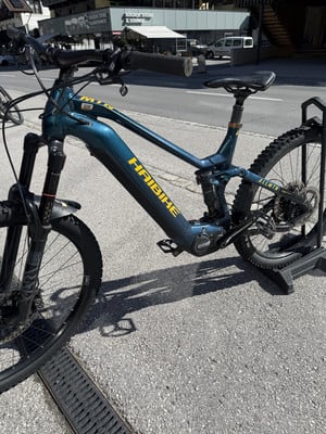 Ein blaues E-Mountainbike der Marke Haibike steht auf einem Ständer auf Asphalt. Ein blaues E-Mountainbike der Marke Haibike steht auf einem Ständer auf Asphalt.