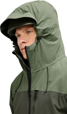 Mann in grüner Kapuzenjacke, Nahaufnahme von Gesicht und Reißverschluss. Mann in grüner Kapuzenjacke, Nahaufnahme von Gesicht und Reißverschluss.
