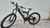 Ein schwarzes KTM E-Mountainbike mit orangefarbenen Akzenten steht vor einer Wand.
