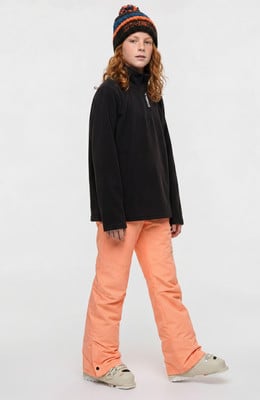Mädchen in schwarzem Fleece-Oberteil, orangefarbener Skihose und Mütze.