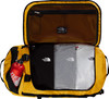 Gelbe Tasche mit offenem Deckel, darin drei T-Shirts und eine Flasche.