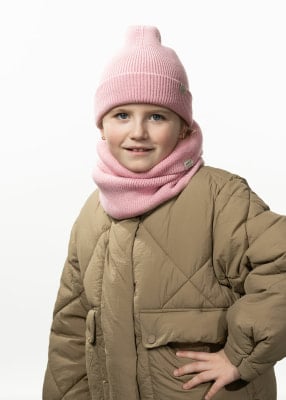 Ein Mädchen in einer rosa Mütze und einem Schal, in einer gesteppten Jacke.