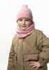 Ein Mädchen in einer rosa Mütze und einem Schal, in einer gesteppten Jacke.