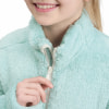 Ein Mädchen schließt eine weiche, hellblaue Fleecejacke am Hals.