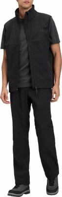 Ein Mann in schwarzer Hose, Weste und T-Shirt trägt Wanderschuhe. Ein Mann in schwarzer Hose, Weste und T-Shirt trägt Wanderschuhe.